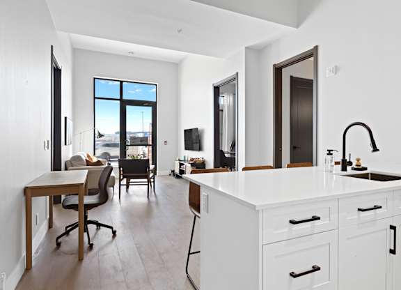 A modern kitchen with white cabinets and a large window.