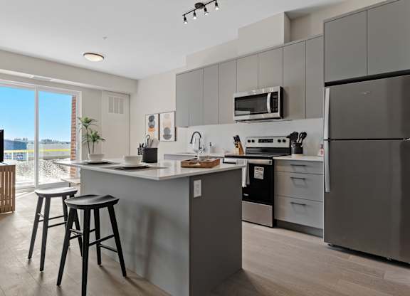 A modern kitchen with a refrigerator, microwave, and stove.