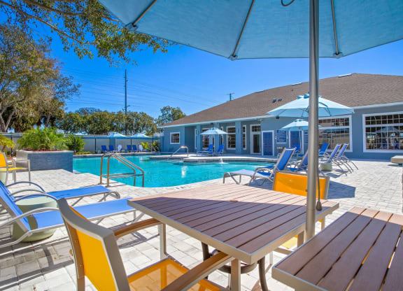 tables and chairs around a pool with the clubhouse in the background at Reserve at Temple Terrace, Temple Terrace, FL