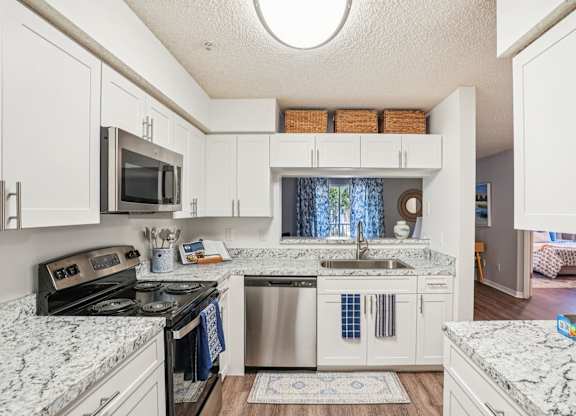 A kitchen with white cabinets and marble countertops.