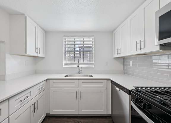 A kitchen with white cabinets and a black stove top.