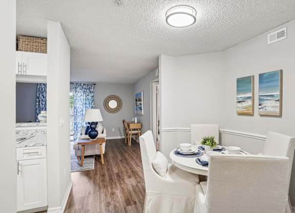 A dining room with a table set for two and a painting on the wall.