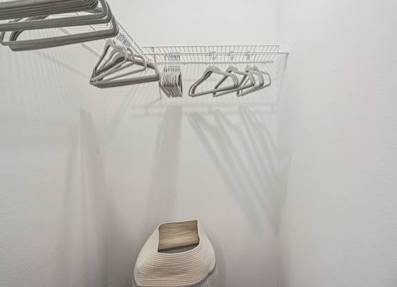 A white chair is under a clothes drying rack.