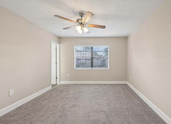 A room with a ceiling fan and a window with blinds.