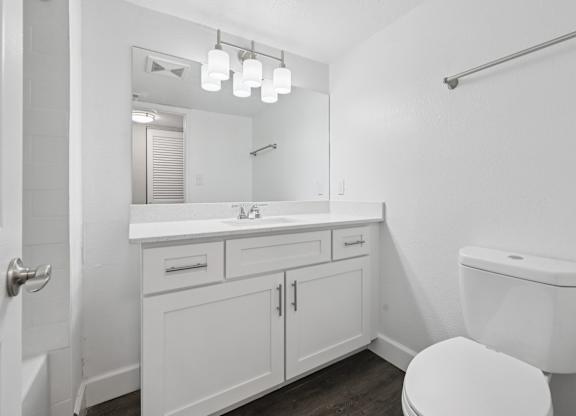 A white bathroom with a toilet, sink, and mirror.