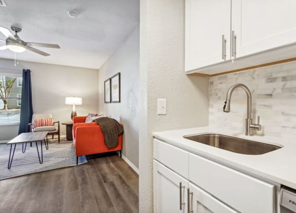 a kitchen with white cabinets and a sink and a living room at Reserve at Temple Terrace, Temple Terrace, FL