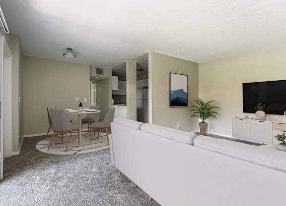 A living room with a grey sofa and a dining table with chairs.