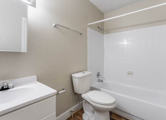 A white toilet sits next to a white sink in a small bathroom.