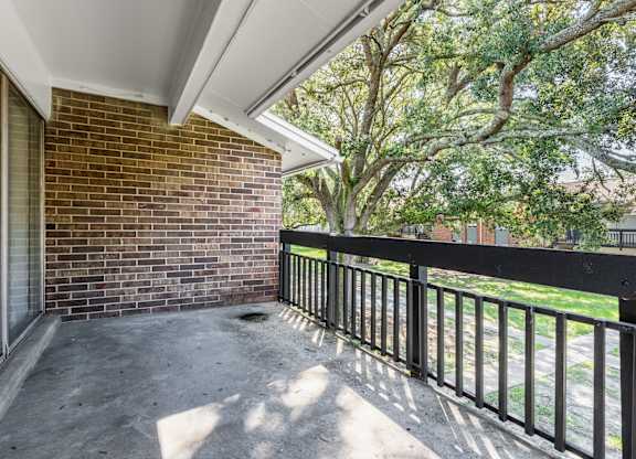 A balcony with a black railing and a brick wall.