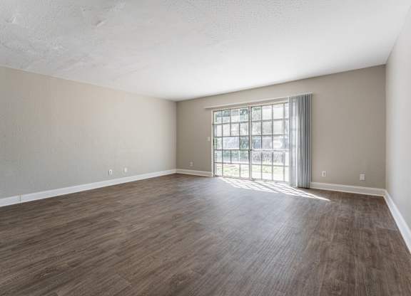 A room with wooden flooring and a large window.