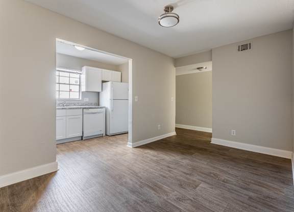 A kitchen with white appliances and a window is visible from a living room.