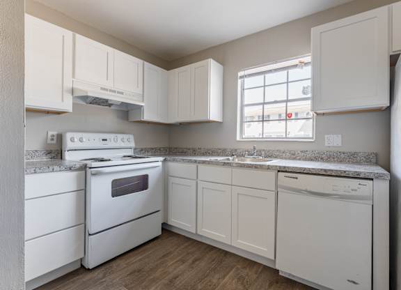 A white kitchen with a stove, oven, dishwasher, and refrigerator.