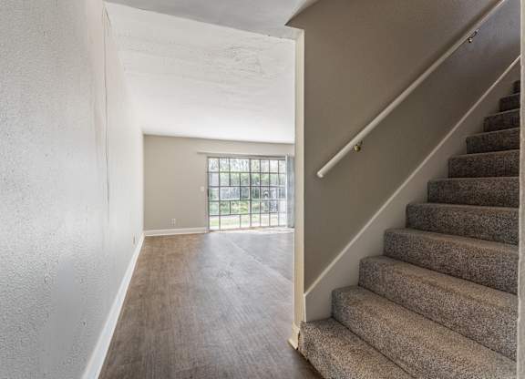 A staircase with a carpeted runner and a window with bars.