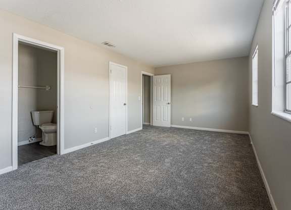 A room with a carpeted floor and a window on the right side.