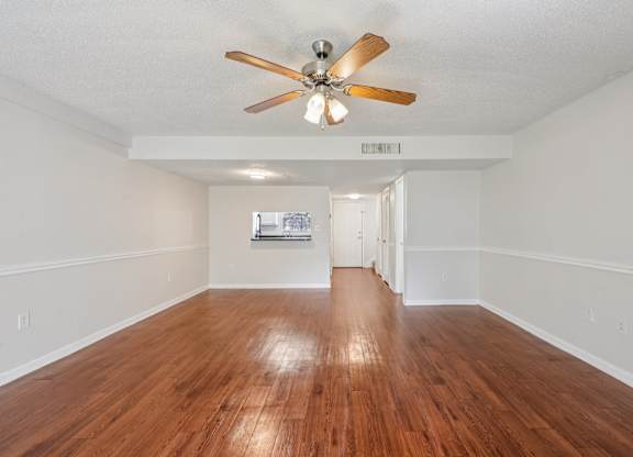 A room with a ceiling fan and wooden floors.