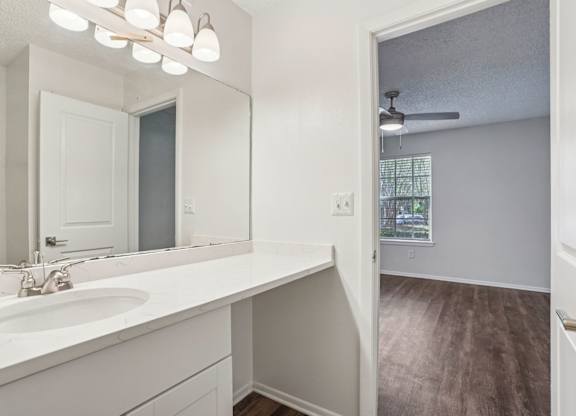 A bathroom with a white sink and mirror.