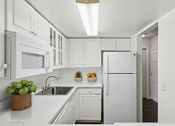 A white kitchen with a refrigerator, sink, and microwave.