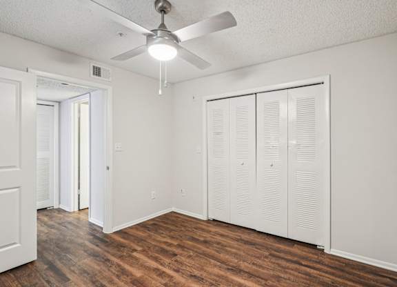 A room with a ceiling fan and wooden floors.