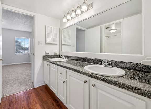 A bathroom with a sink, mirror, and wooden floors.