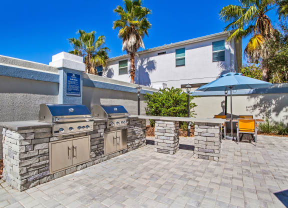 the outdoor patio has a barbecue grill and a table with umbrellas at Reserve at Temple Terrace, Temple Terrace