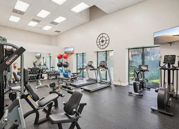 A spacious gym with a variety of equipment including treadmills, stationary bikes, and weight machines.