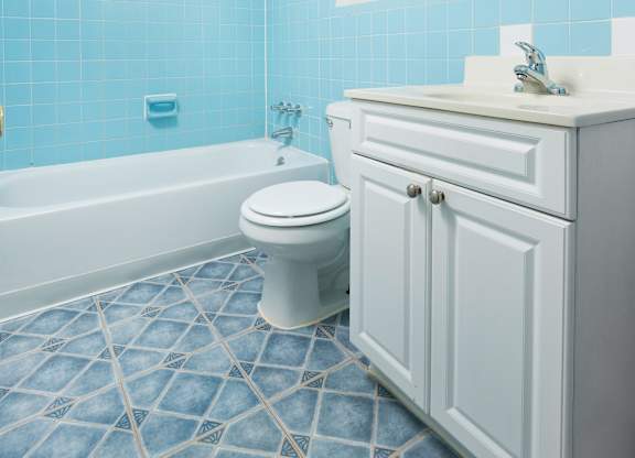 A white toilet sits in a blue tiled bathroom.