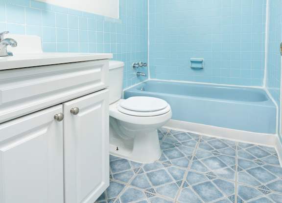 A white toilet in a blue tiled bathroom.