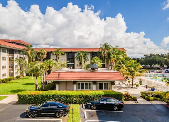 Two black cars parked in front of a building with a red roof.