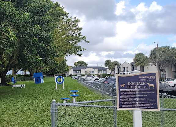 a park with a sign and chairs in the grass