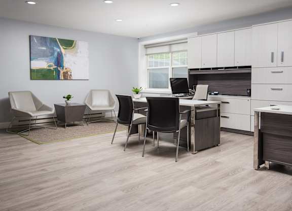 A modern office space with a desk, chairs, and a painting on the wall.