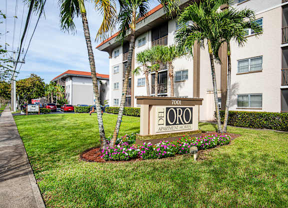 A sign for Del Oro Apartment Homes is in front of a building with a landscaped area.