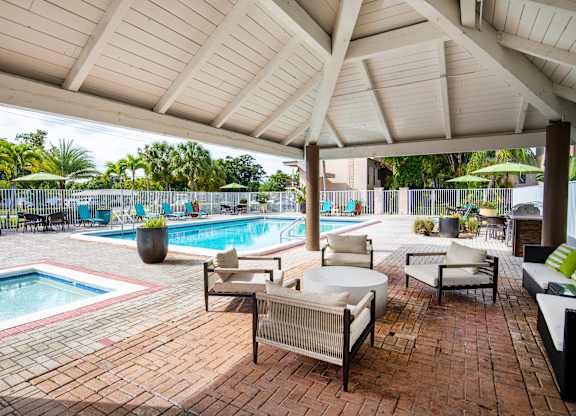 A patio with a pool and a white umbrella.