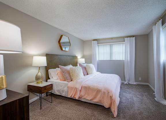 A bedroom with a bed, nightstand, and lamp.