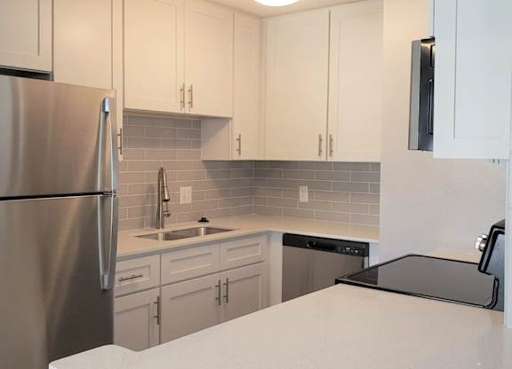A kitchen with a stainless steel refrigerator and white cabinets.