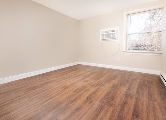 Empty room with wooden flooring and a window.