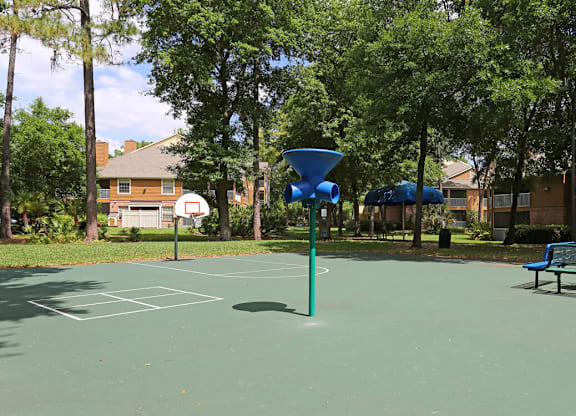 A basketball court with a blue hoop and a bench.