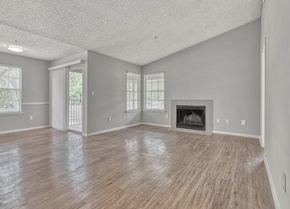 A spacious living room with wood flooring and a fireplace.