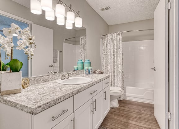 A bathroom with a marble countertop and white cabinets.