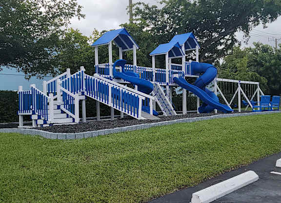 a playground with a blue set of slides in a parking lot