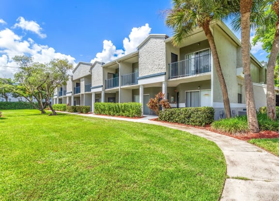 a sidewalk in front of an apartment building with palm trees at Waterford Park Apartment Homes, LLC, Lauderhill, FL 33319