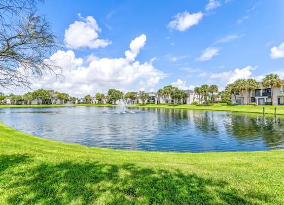 a lake with a fountain in the middle of a grassy field at Waterford Park Apartment Homes, LLC, Lauderhill Florida