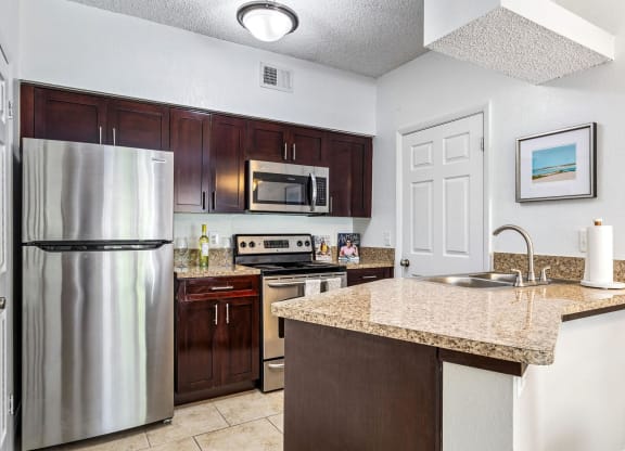 a kitchen with stainless steel appliances and a granite counter top at Waterford Park Apartment Homes, LLC, Florida