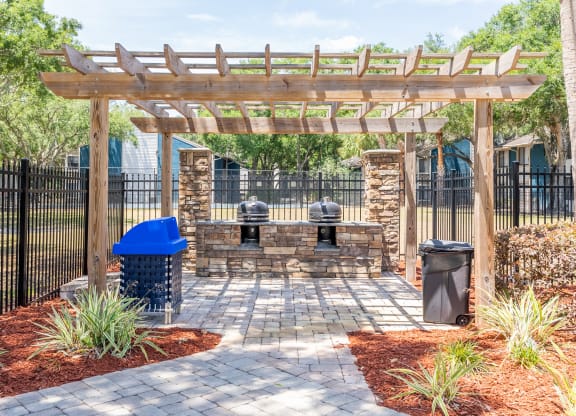 a patio with a stone fireplace and a wooden pergola  at Fisherman's Landing Apartment Homes, Tampa, Florida