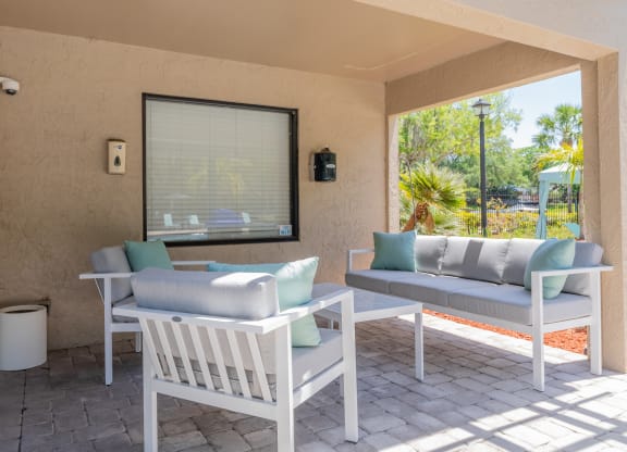 a covered patio with two chairs and a table  at Fisherman's Landing Apartment Homes, Florida