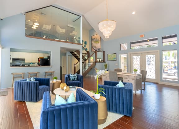 a living room with blue couches and chairs and a kitchen  at Fisherman's Landing Apartment Homes, Tampa, FL
