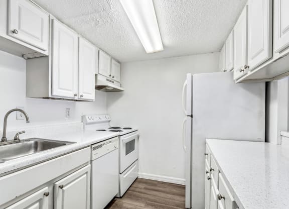 a kitchen with white cabinets and a sink and a refrigerator at Greenwich Commons Apartment Homes, Tampa, FL, 33613