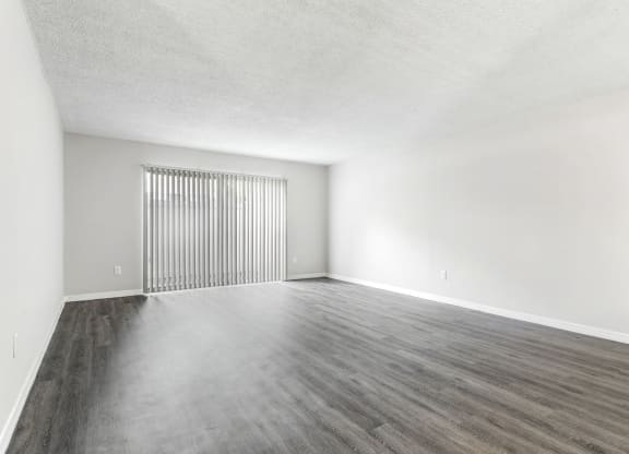 an empty living room with white walls and wood floors at Greenwich Commons Apartment Homes, Florida