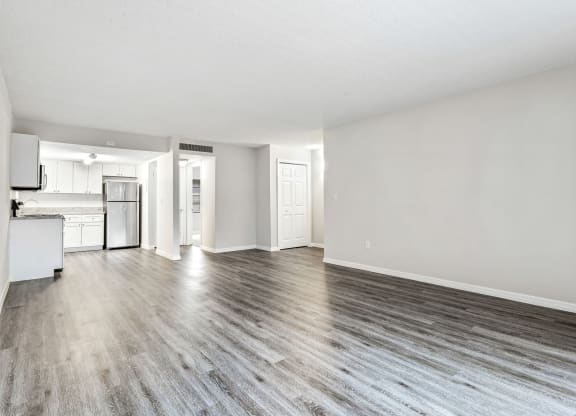 an empty living room and kitchen with white walls and wood floors at Greenwich Commons Apartment Homes, Tampa, FL, 33613