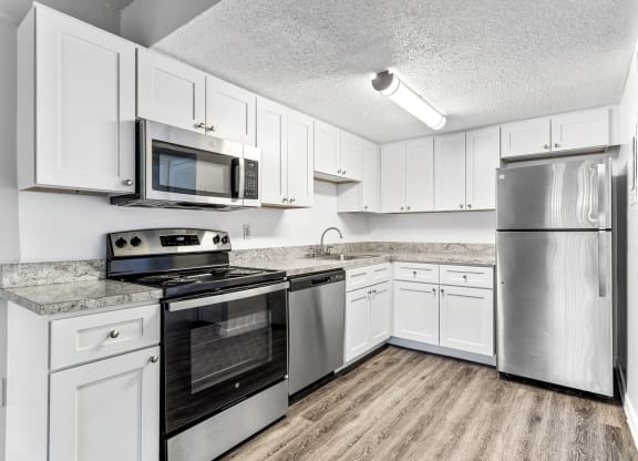 a kitchen with stainless steel appliances and white cabinets at Greenwich Commons Apartment Homes, Tampa