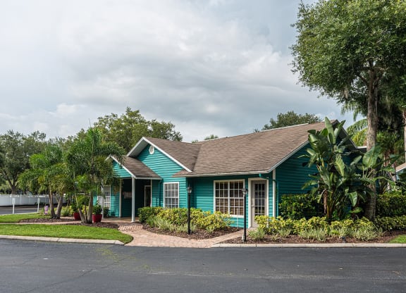 a green house with trees and a road in front of it at Madison Oaks Apartment Homes, LLC, Palm Harbor, FL 34684